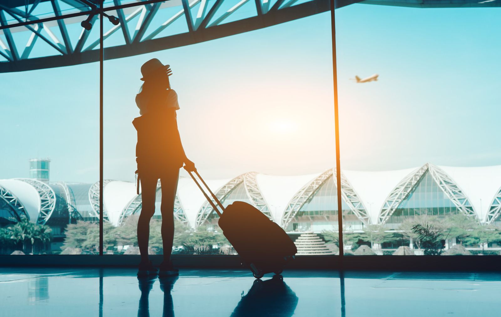 Traveller at an airport window watching a plane take off